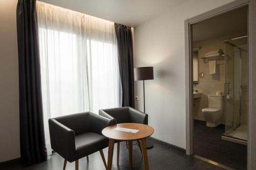 Habitación con silla, mesa y ventana en Hotel Lux Santiago, en Santiago de Compostela