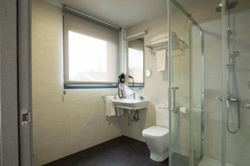 a bathroom with a toilet and a sink and a shower at Hotel Lux Santiago in Santiago de Compostela