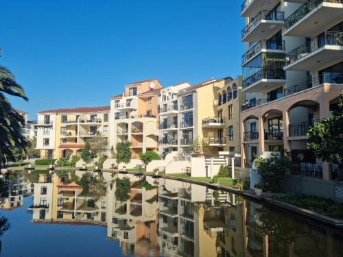 a row of apartment buildings next to a body of water at Island Club by Smart City Stays in Cape Town