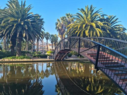 a bridge over a body of water with palm trees at Island Club by Smart City Stays in Cape Town