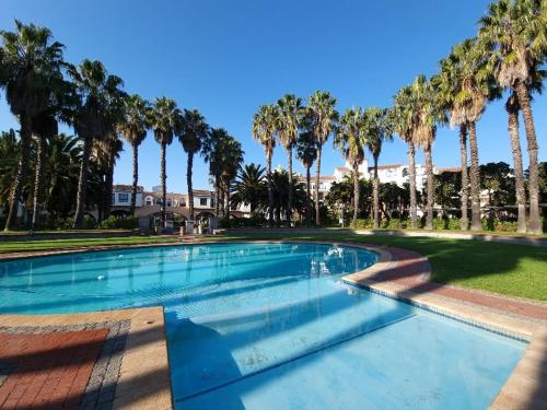 a swimming pool with palm trees in a park at Island Club by Smart City Stays in Cape Town