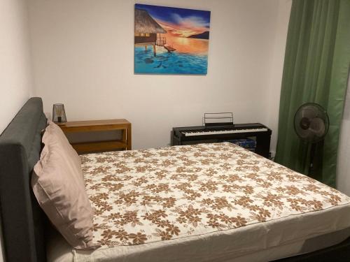 a bedroom with a bed and a painting on the wall at Standing Residence Kumuhei in Papeete