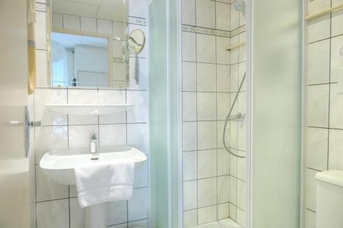 a white bathroom with a sink and a shower at Logis hôtel restaurant de Provence in Orange