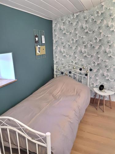 - une chambre avec un lit et un mur orné de fleurs dans l'établissement Gites de la Bonaudrie, à Combrand