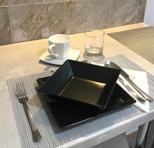 a black plate on a table with a glass of water at Check-In Kaya in Sibiu