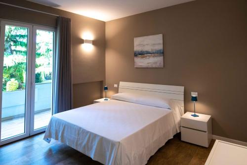 Sirmio Apartments - Narnia Stay في سيرمِيوني: غرفة نوم بسرير ابيض ونافذة كبيرة