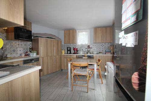 une cuisine avec une table et des chaises dans l'établissement Le tilleul de St Julien, à Saint-Julien-de-Chédon
