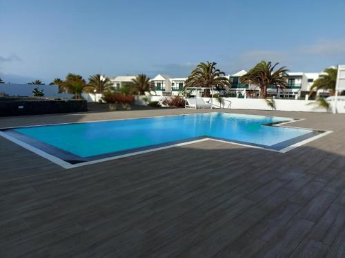 een zwembad met blauw water op een houten terras bij White Suite Deluxe in Costa Teguise