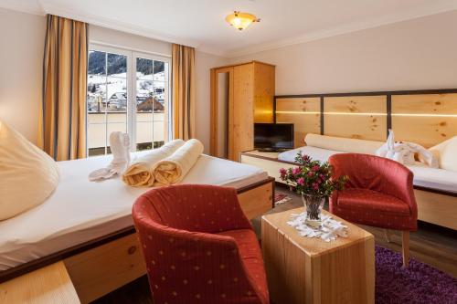 um quarto de hotel com duas camas e duas cadeiras em Hotel Garni Ida em Ischgl