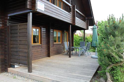Casa con terraza de madera con mesa y sillas en Holzblockhaus mit Kamin am Kite , Surf und Badestrand, en Loissin