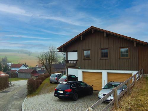 a house with two cars parked in front of it at Ferienwohnung am Wirtsgarten in Bad Birnbach