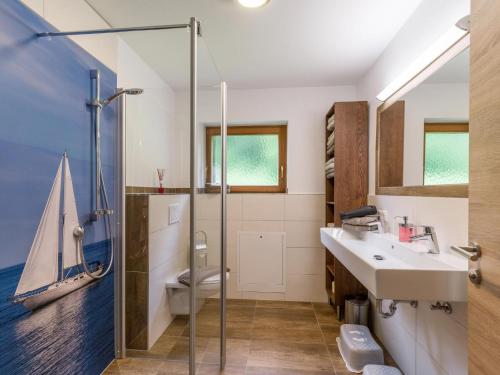 a bathroom with a sink and a shower with a sailboat on the wall at Ferienhaus am Erlachhof in Söll