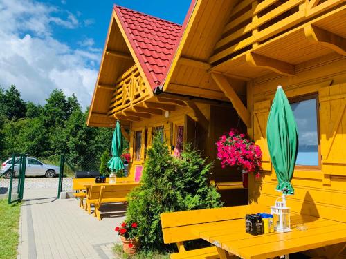żółty budynek ze stołami i parasolami w obiekcie Złoty Brzeg Wicie w Wiciu