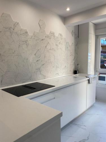 a kitchen with white counters and a stone wall at Apartamento M Garaje Playa Golf in Zarautz