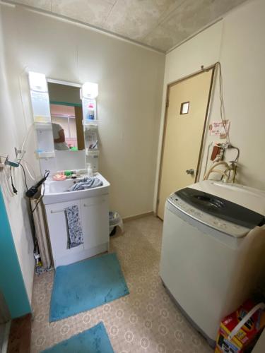 a bathroom with a sink and a washing machine at メゾン102号 Mason Guest House Suite 102 in Matsudo