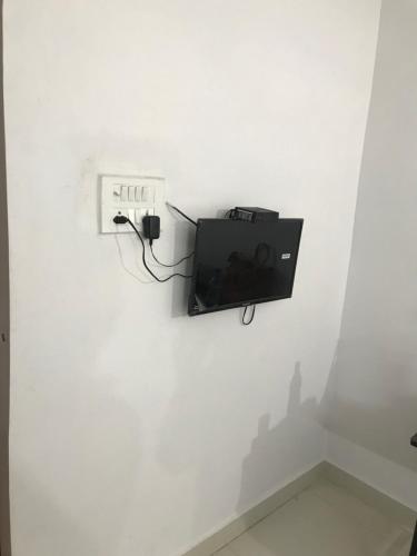 een tv aan een muur in een witte muur bij Prestige Guest House & Hostel in Bilāspur