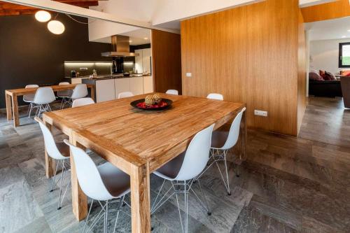 a dining room with a wooden table and white chairs at La Solfa casa aislada con piscina y jardín in Les Preses