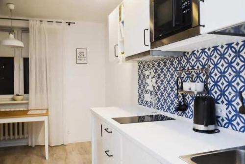 una cocina con armarios blancos y azulejos azules y blancos en Apartamenty Centrum, en Varsovia