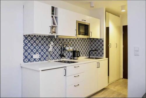 cocina con armarios blancos y microondas en Apartamenty Centrum, en Varsovia