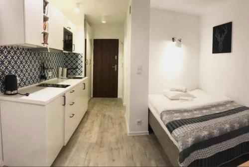 una pequeña cocina blanca con cama y lavabo en Apartamenty Centrum, en Varsovia