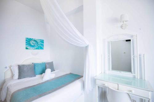 a white bedroom with a bed and a mirror at Kafieris View in Firostefani