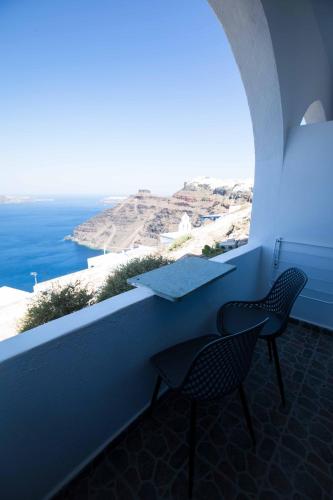 a table and chair on a balcony with a view of the ocean at Kafieris View in Firostefani