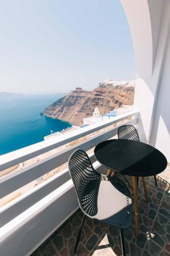 a table and chairs on a balcony overlooking the ocean at Kafieris View in Firostefani