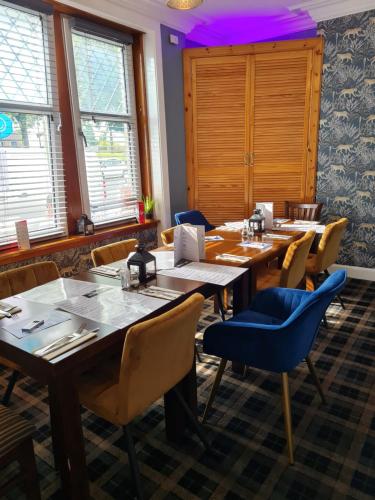 a dining room with tables and chairs and windows at The Market Inn Hotel in Castle Douglas