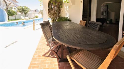 a wooden table and chairs on a patio with a pool at Villa Pedro - Swimming Pool - BY BEDZY in Albufeira