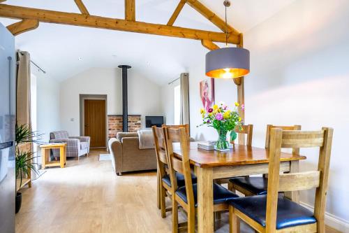a dining room and living room with a table and chairs at Brecks Farm - The Tractor Shed in York