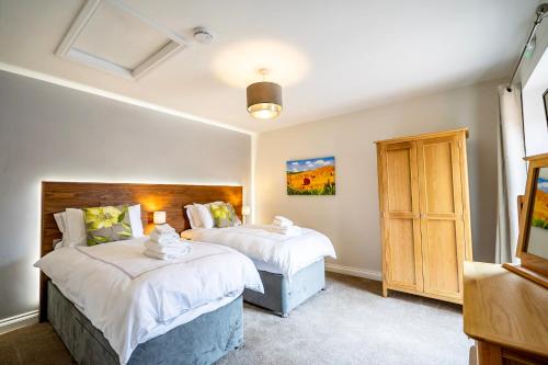 a bedroom with two beds and a cabinet at Brecks Farm - The Tractor Shed in York