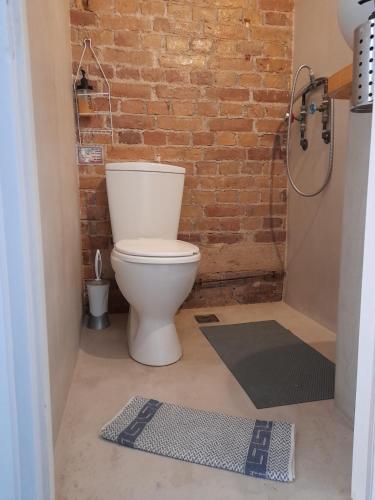 ein Badezimmer mit Toilette und einer Ziegelwand in der Unterkunft STUDIO PORTO in Korfu-Stadt