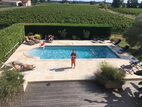 a woman standing in front of a swimming pool at Château la Renommée in Saint-Laurent-des-Combes