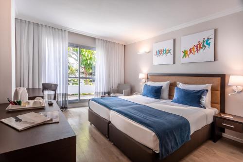 a hotel room with a large bed and a desk at Kfar Maccabiah Business & Sport Hotel in Ramat Gan