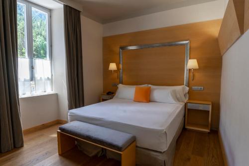 a bedroom with a large white bed with orange pillows at Gran Hotel – Balneario de Panticosa in Panticosa