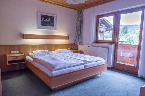 a bedroom with a large bed and a window at Die Pension - Margreiter in Saalbach-Hinterglemm