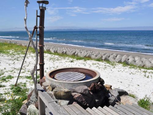 a fire pit on the beach next to the ocean at Pension Arumeria in Wakkanai