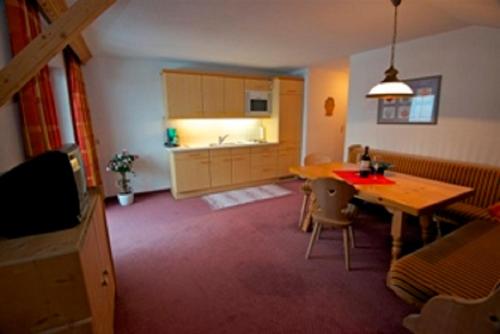 a living room with a table and a kitchen at Ferienwohnungen Wolf in Holzgau