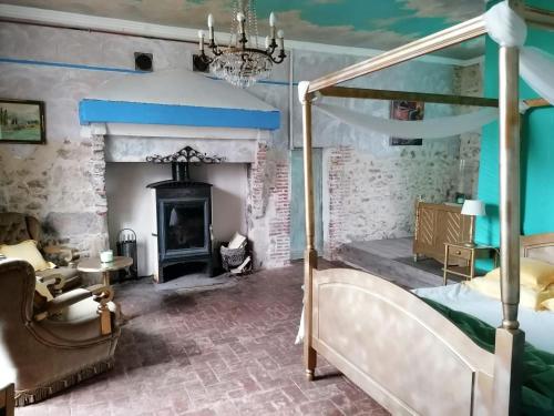 a bedroom with a canopy bed and a fireplace at Hôtellerie Jardiniers Gourmands in Morsains