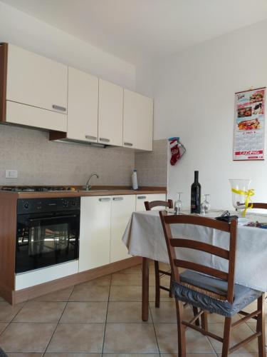 a kitchen with white cabinets and a table with chairs at LA CALA in Olbia