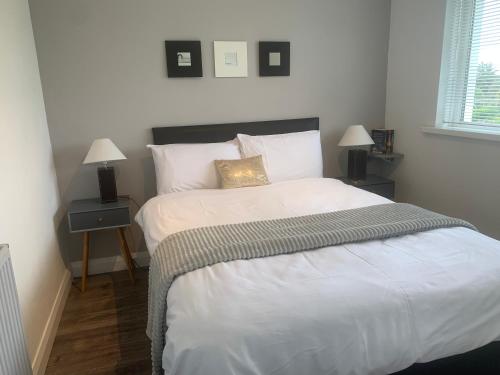 1 dormitorio con 1 cama grande con sábanas y almohadas blancas en Hillcrest House Self Catering Apartments, en Donegal