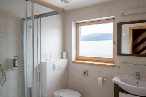 een badkamer met een toilet, een wastafel en een raam bij Penzion Damisport in Donovaly