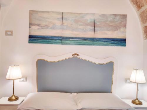 a bedroom with a bed with three paintings on the wall at RomAntica in Polignano a Mare