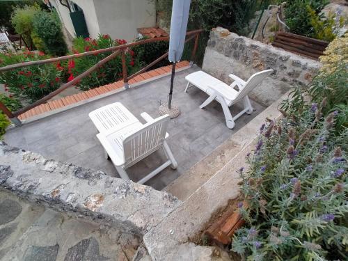 two white chairs and an umbrella on a patio at CASA SAN ROCCO in Porto Ercole
