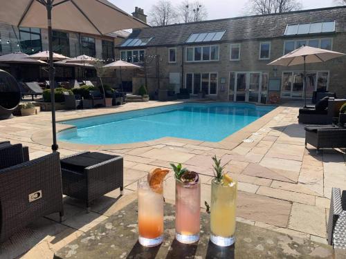 two drinks on a table next to a swimming pool at Feversham Arms Hotel & Verbena Spa in Helmsley