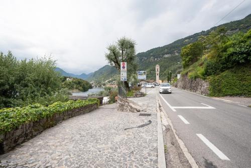 a car driving down a road next to a river at Lake Como Studio with Balcony and Private Parking in Ossuccio