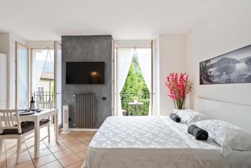 een slaapkamer met een bed, een bureau en een televisie bij Lake Como Studio with Balcony and Private Parking in Ossuccio