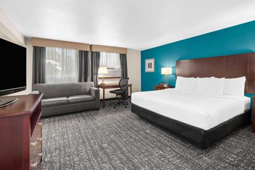 a hotel room with a bed and a couch and a desk at La Quinta by Wyndham Portland NW in Portland