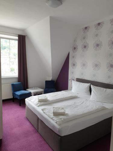 a bedroom with a large bed and a blue chair at Haus Burgfrieden Cochem in Cochem