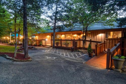 a house with a porch and a fence and trees at Cabins at Green Mountain, Trademark Collection by Wyndham in Branson